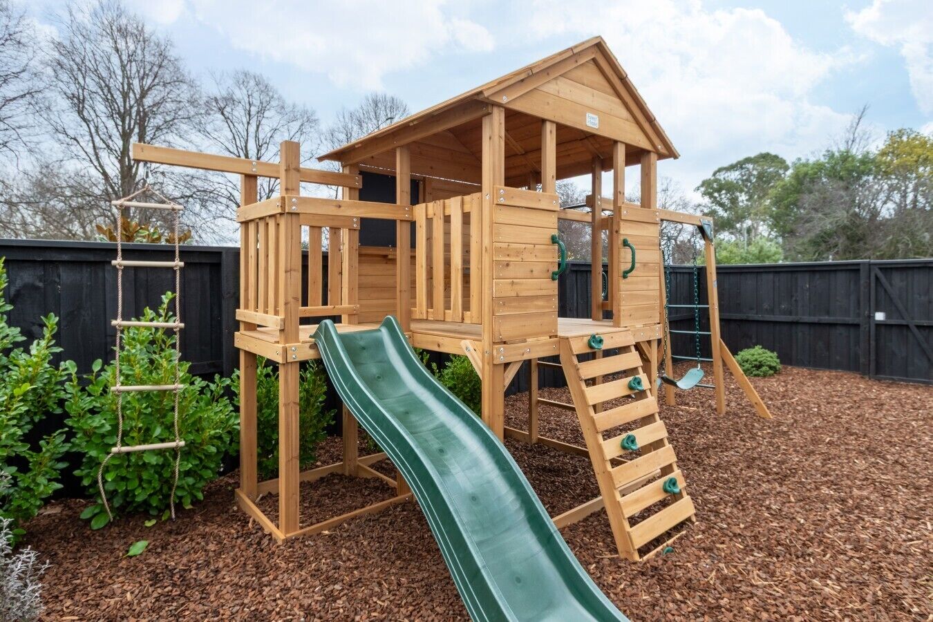 A wooden play structure with a slide, climbing ladder, and multiple platforms.