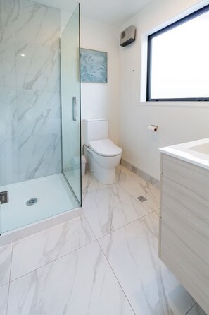 Ein modernes Badezimmer mit Glasdusche, Toilette und Waschbecken.