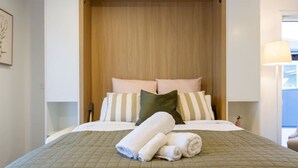 Una cama bien hecha con colcha verde acolchada, dos almohadas y toallas enrolladas.