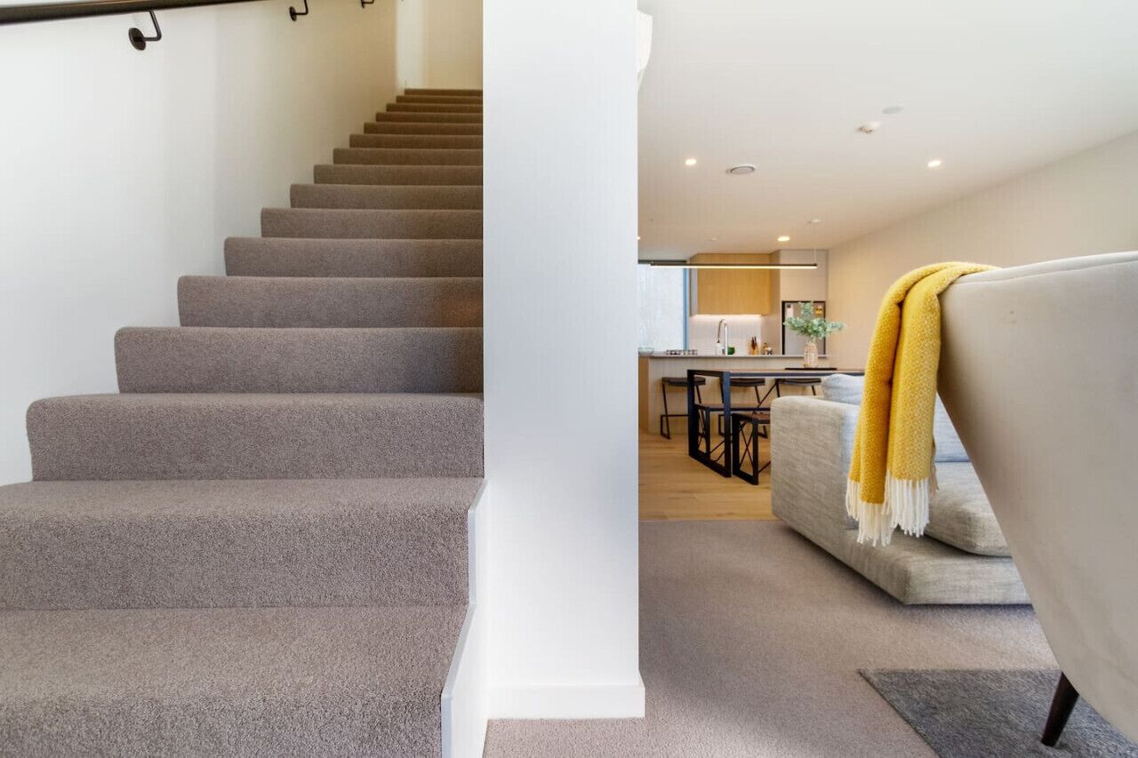 Una escalera conduce a una sala de estar con un sofá y una manta amarilla.