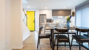 A modern kitchen with a microwave, refrigerator, and a dining area with a table and chairs. - Urban comfort and parking near Avebury Park (Christchurch)