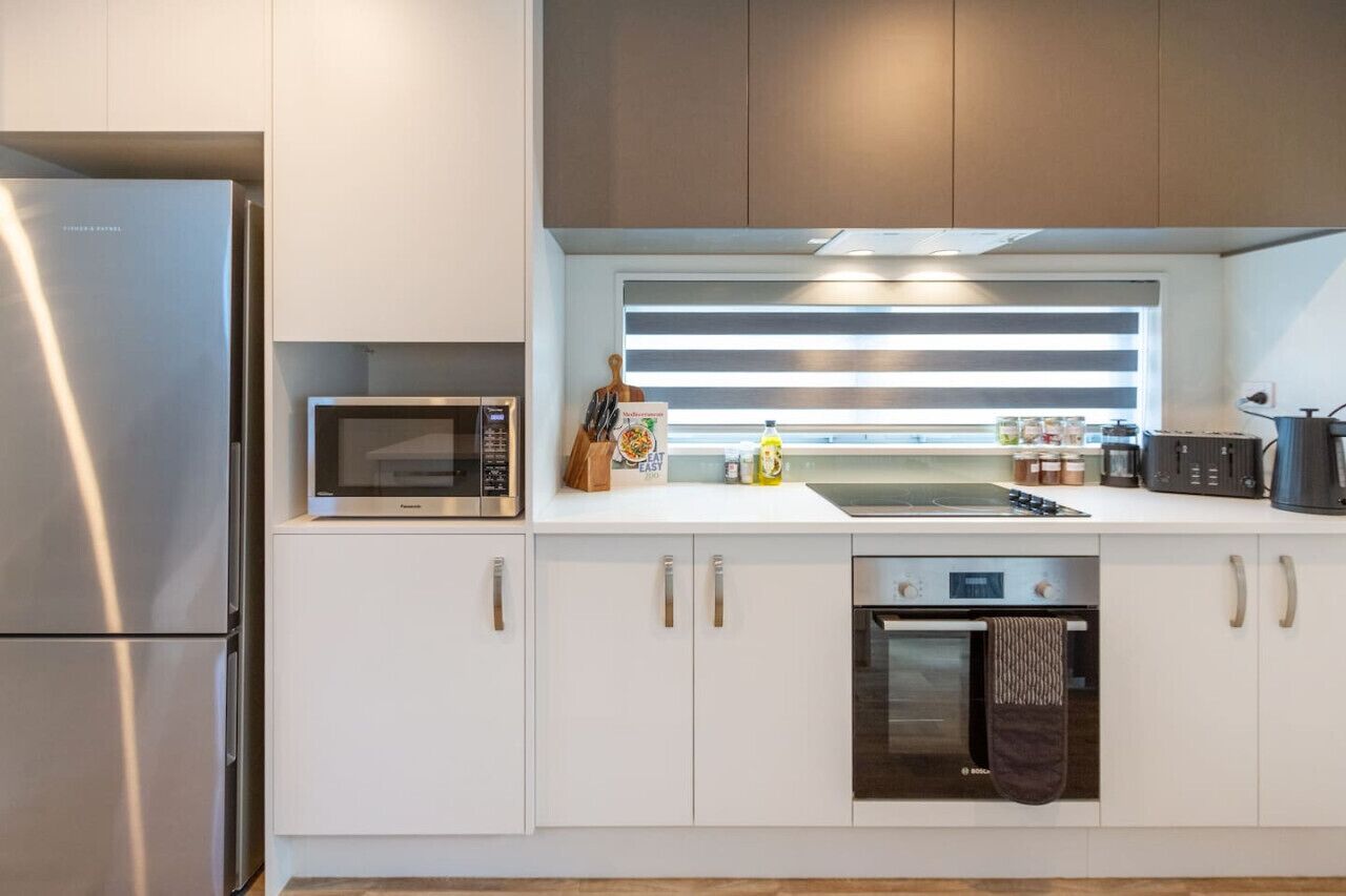 A modern kitchen with white cabinets, stainless steel appliances, a microwave, and a toaster.
