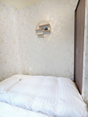 A bedroom with a bed, a circular wall-mounted shelf, and a wardrobe.
