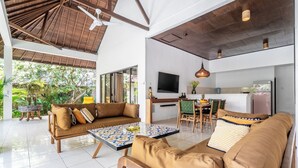 A spacious living area with a high ceiling, a sofa set, a dining table, and a kitchen area. - Villa Amaro - 2 Bedrooms (Seminyak)