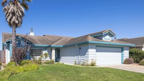 Einbungalow mit Garage, Rasen und einer Palme.