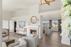 A spacious living room with a fireplace, a dining area, and a view of the outdoors. - Stay Close to The Beach at Marina's Sand Piper! (Marina)