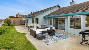 Eine Terrasse mit Gartenmöbeln, einem Grill und Blick auf den Garten.
