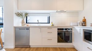 Une cuisine moderne avec des meubles blancs, un lave-vaisselle, un four et un four à micro-ondes.