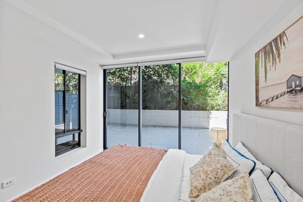 A bedroom with a bed, a window, and a view of greenery outside.