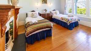 Une chambre avec deux lits, une commode en bois, un vase et un tableau au mur.