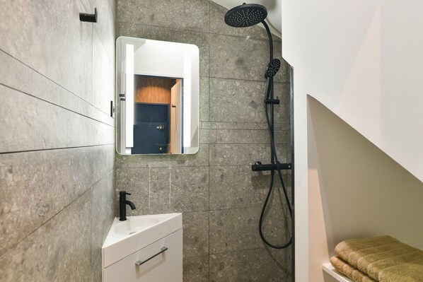 A bathroom with a white sink, a mirror, and a shower with a handheld showerhead. - TBS 18 - Fabulous suite in the Marais Quarter (Paris)