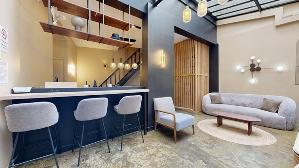 A modern kitchen with a bar area, bar stools, a sofa, and a coffee table. - TBS 242 - Exceptional triplex loft (Paris)