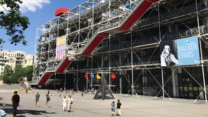 A modern building with scaffolding, a large billboard, and a pedestrian area.