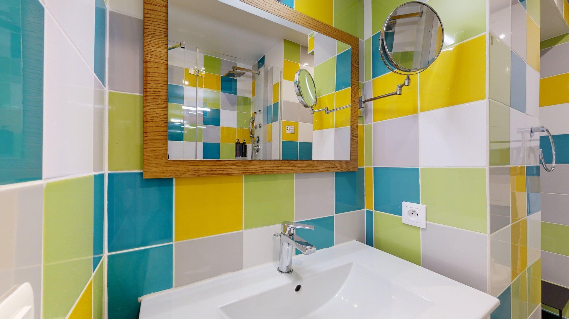 A bathroom with a white sink, a mirror, and colorful tiles.