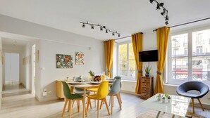 A modern dining area with a table set for four, yellow chairs, and a TV on the wall.