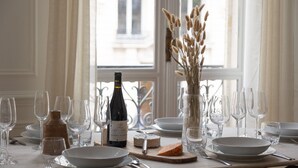 A dining table set with wine glasses, a bottle of Saint Marc Cabernet Sauvignon, a cheese, and a vase with dried flowers. - TheBlueStay 153 - Outstanding spacious suite - A/C (Paris)