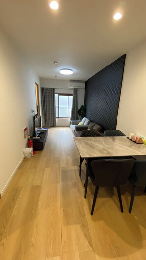 Uma sala de estar moderna com área de jantar, uma janela grande e uma parede escura com textura.