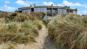 Ein Küstenhaus mit einem Sandweg, umgeben von hohem Gras.
