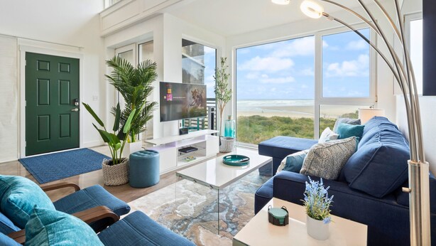 Ein modernes Wohnzimmer mit großem Fenster, Flachbildfernseher und blauem Sofa.