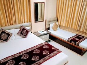 Une chambre d’hôtel avec deux lits, des rideaux beiges, une table de chevet avec une télécommande et un miroir au mur.