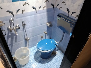 Une salle de bain avec des toilettes bleues, un lavabo et une poubelle.