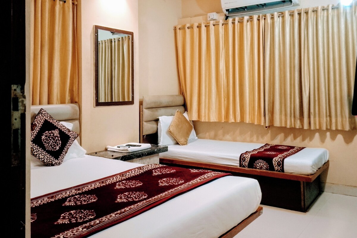 Une chambre d’hôtel avec deux lits, un ventilateur de plafond, un appareil de climatisation et une fenêtre avec des rideaux.
