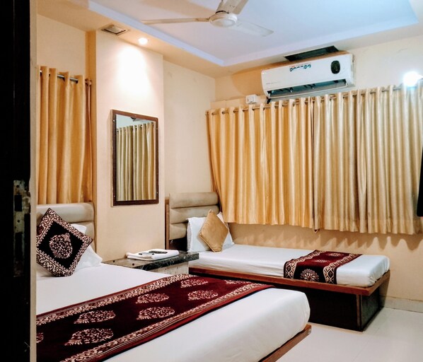 Une chambre d’hôtel avec deux lits, un ventilateur de plafond, un appareil de climatisation et une fenêtre avec des rideaux.