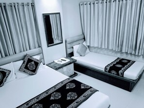 Une chambre d’hôtel avec deux lits, une table de chevet, un miroir et des rideaux.