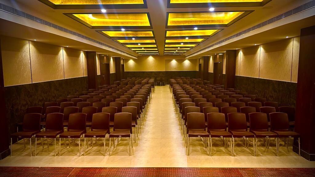 Una sala de conferències amb files de cadires, un passadís central i una catifa amb disseny.