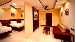 Una habitación de hotel moderna con dos camas, un sofá, una mesita de centro y ventiladores de techo.