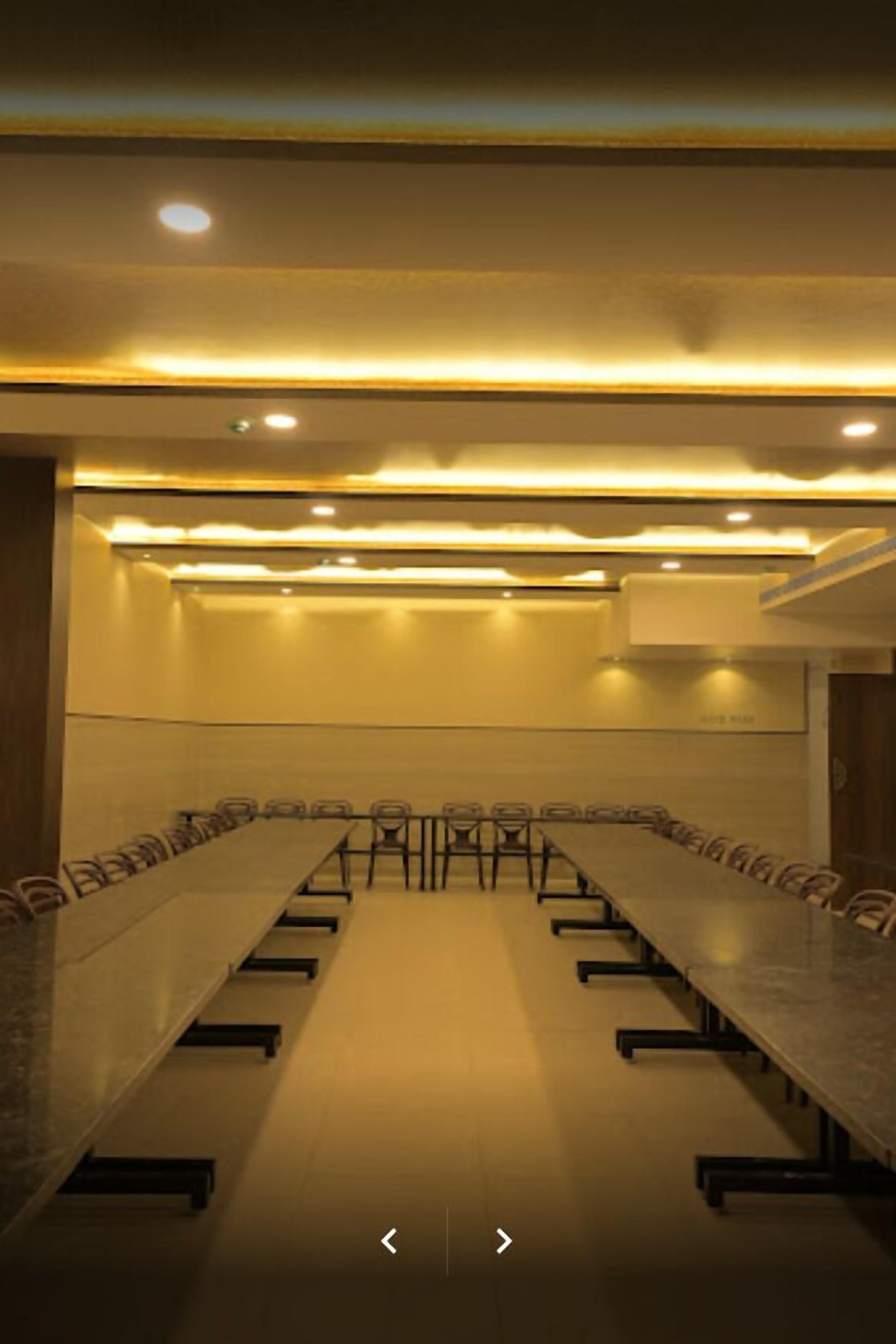 A conference room with a long table, chairs, and recessed lighting.