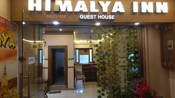 La entrada a la Casa de Huéspedes Himalaya Inn, con una puerta de cristal transparente, un mostrador de recepción en el interior y plantas decorativas.