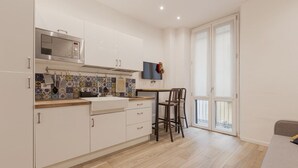 A modern kitchen with white cabinets, a stainless steel microwave, and a tiled backsplash. - GuestHost - Lovely and cosy apartment near Porta Romana (Milano)