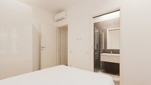 A bedroom with a bed, a door, and a bathroom visible through an open door. - GuestHost - Lovely and cosy apartment near Porta Romana (Milano)