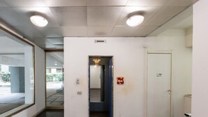 A hallway with a door, a fire alarm, and a ceiling light fixture. - Bright apartment of about 65sqm, located on the first floor of a building with elevator (NOT suitable for disabled) can accommodate up to 2 people.Once inside you will be welcomed by a modern and comfortable, equipped with every comfort.The property is l (Cagliari)