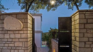 A stone pathway leading to a gated entrance with a sign that reads "VILLA NOVA."