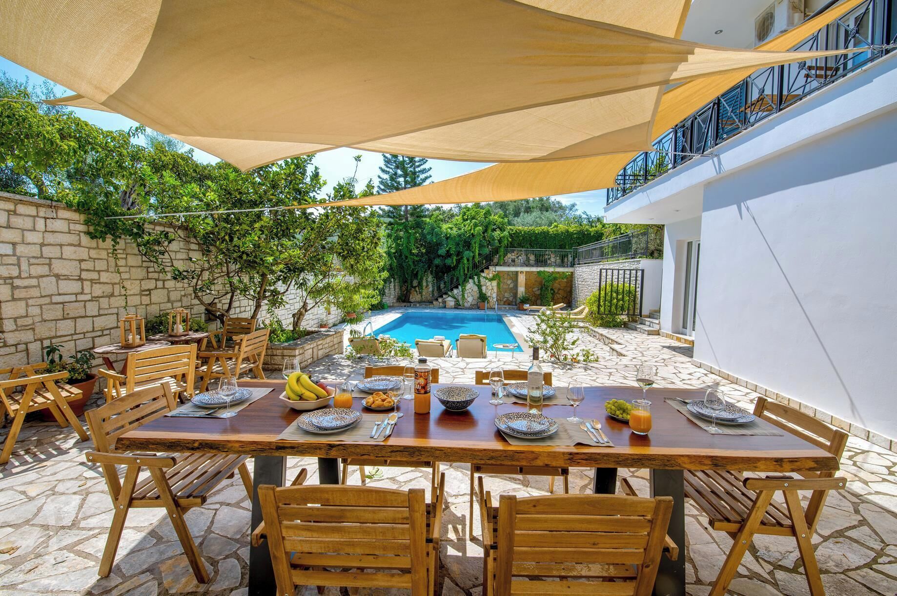 Un área de comedor al aire libre con piscina al fondo.