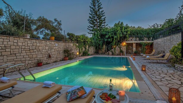 A swimming pool with lounge chairs and a table with food and drinks.