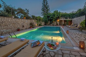 A swimming pool with lounge chairs and a table with food and drinks. - Villa Nova Paxos (Pac)