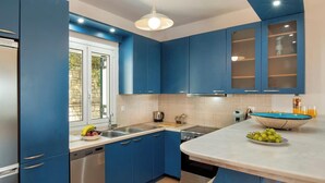 A modern kitchen with blue cabinets, a white countertop, and a built-in dishwasher.
