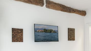 Habitació amb televisió penjada a una paret blanca, acompanyada de dos panells amb relleu.