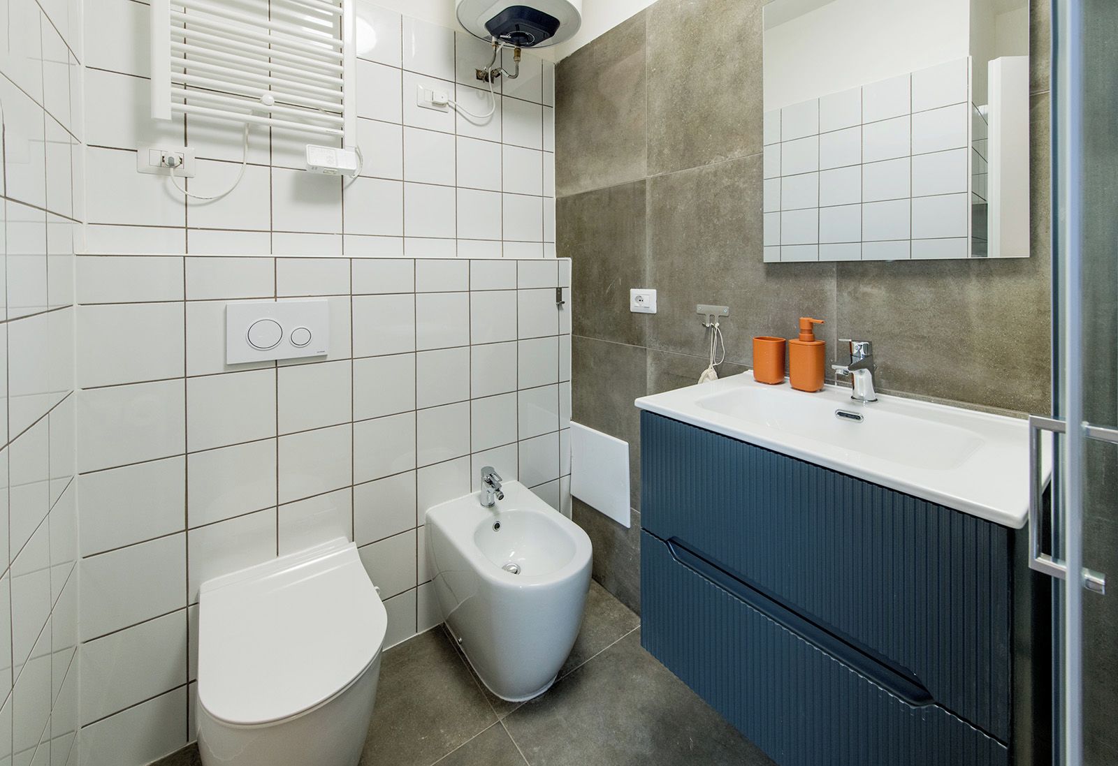 Un bagno moderno con un WC bianco, un bidet e un lavandino con mobili azzurri.