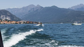 Un pueblo costero con edificios a lo largo del muelle, un barco en el agua y montañas al fondo.