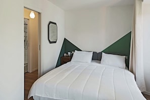 A neatly made bed with white linens, a bedside table with a lamp, and a green accent wall. - Stresa Complex Levoasi (Stresa)