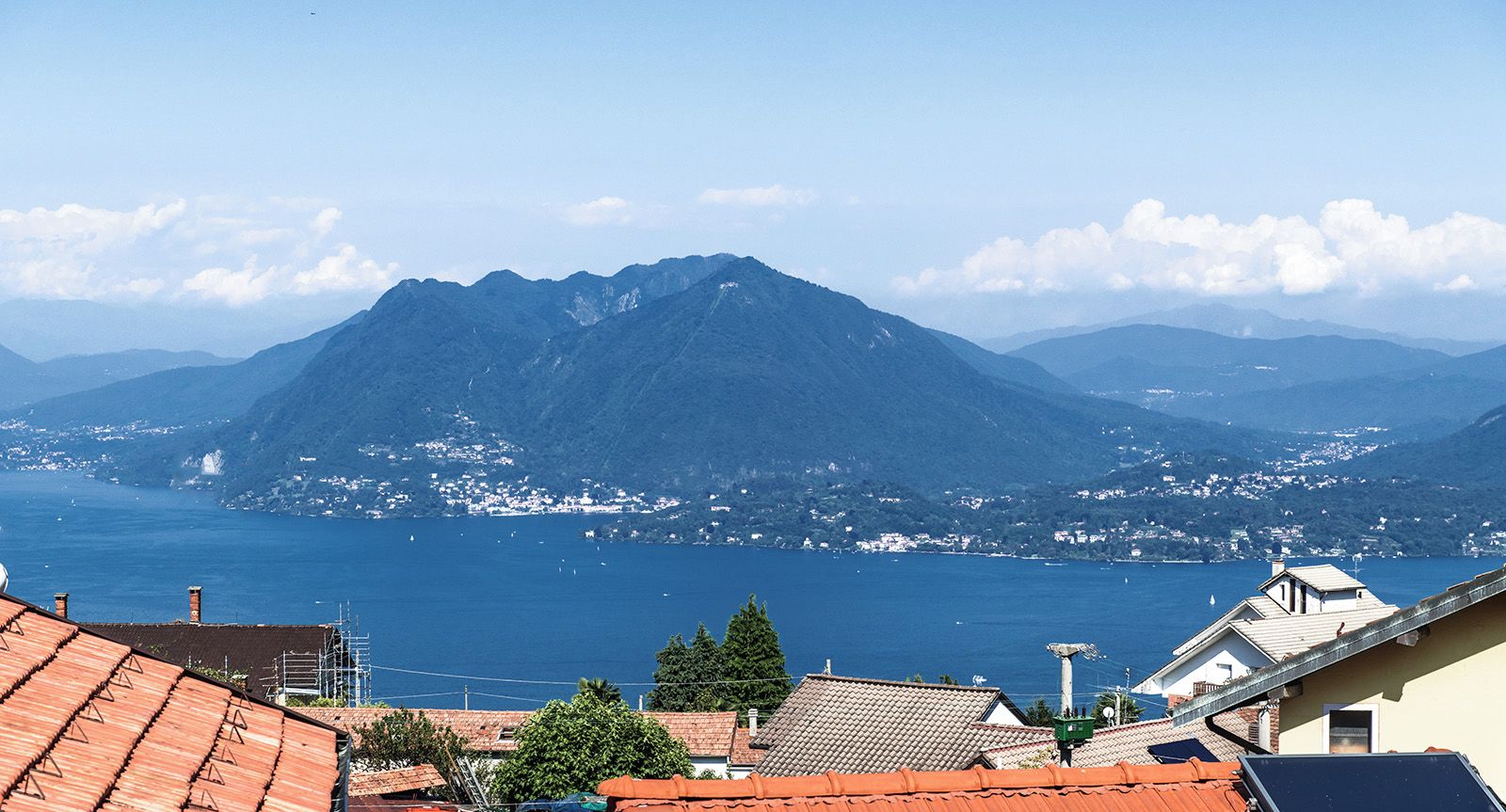 A mountain with a clear view of the sea and a town in the background.
