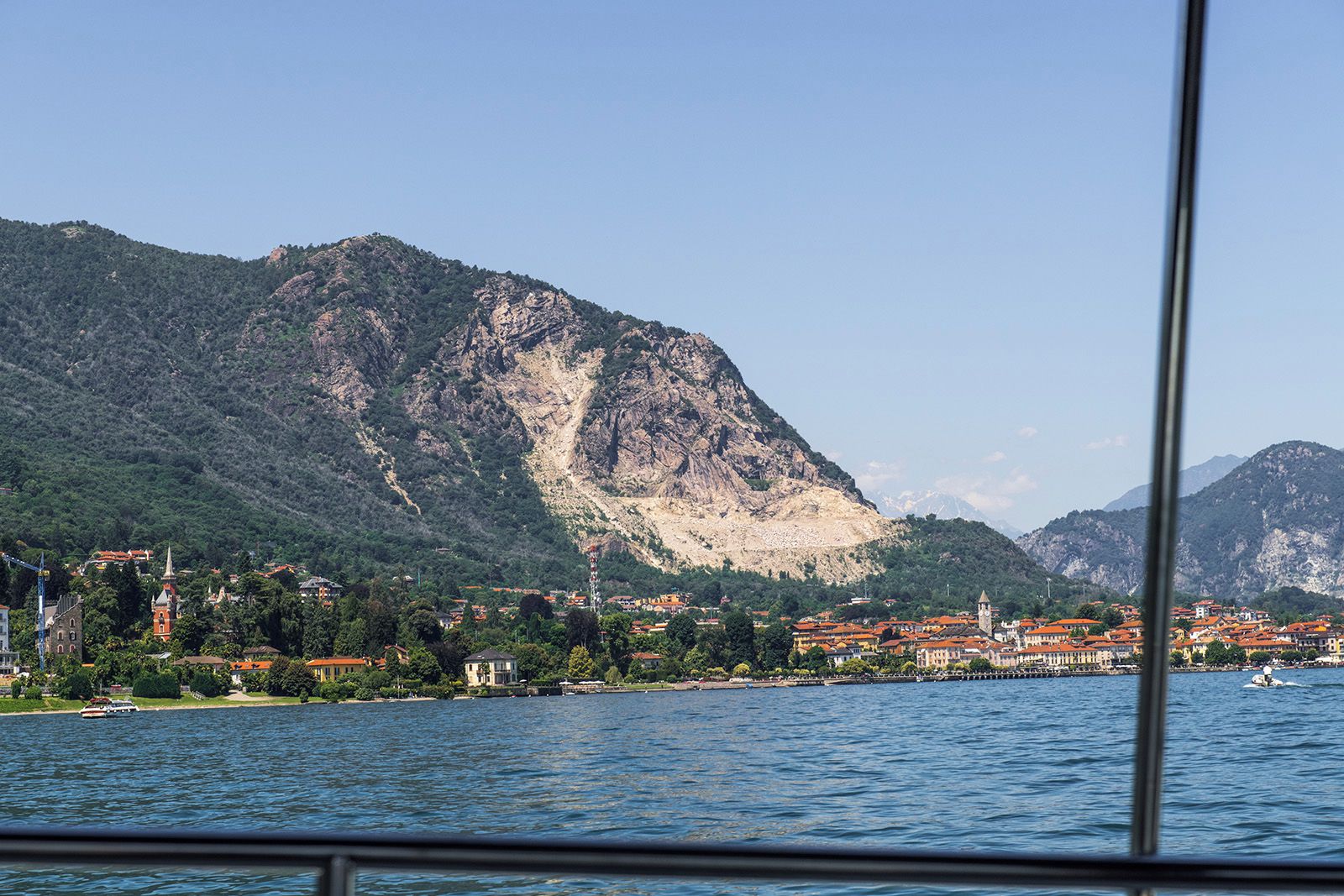 A coastal town with buildings along the waterfront, a prominent mountain in the background, and a clear view of the sea.