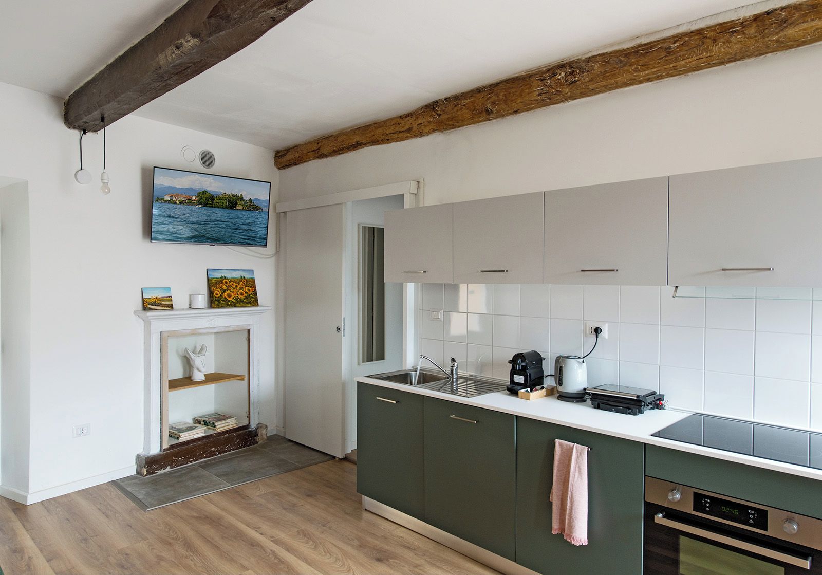 A modern kitchen with a wooden ceiling beam, a built-in oven, and a large window.