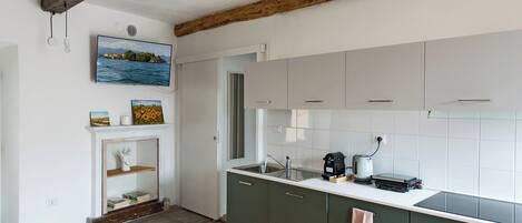 A modern kitchen with a wooden ceiling beam, a built-in oven, and a large window.