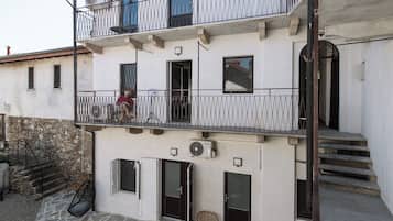 Un edifici de diverses plantes amb balcons, una escalinata de pedra i zones d'estar a l'exterior.