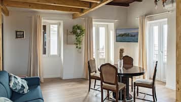 Un salón acogedor con techo de madera, una mesa de comedor con sillas, un sofá azul y un cuadro en la pared.